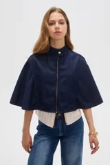 Poncho corto de denim azul con cuello alto, cierre frontal y diseño amplio de inspiración capa.