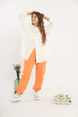 Camisa blanca amplia de manga larga con ruedo curvo.