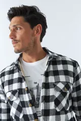 Sobrecamisa de algodón a cuadros color ladrillo, con interior de corderito, cierre con botones, bolsillos tipo cartera y logo en goma. El modelo usa talle M.