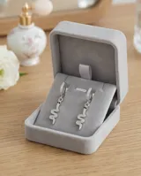 Aros tipo argolla de plata con dije colgante en forma de serpiente, decorados con circonias brillantes y detalles en negro en los ojos.