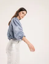 Blusa celeste de cuello mao y mangas abullonadas con puños elásticos. Tiene tajos laterales y botones en la delantera.