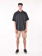 Camisa de manga corta color blanco roto con textura de tejido de lino o similar, corte holgado y cuello camisero.