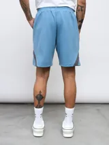 Bermuda deportiva negra de algodón y poliéster, con cintura elástica ajustable con cordón, bolsillos laterales y detalle de recortes geométricos en gris en los laterales. Logo de la marca bordado en la pierna izquierda.