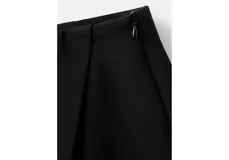 Minifalda negra de tiro medio, con diseño cruzado tipo envolvente (wrap) en el frente.