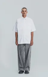 Camisa de manga corta en popelina de algodón, con silueta oversize y diseño funcional que incluye dos bolsillos delanteros, uno de ellos con solapa.