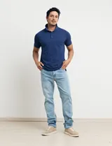 Remera polo azul marino de manga corta, con cuello y tapeta de dos botones. Presenta aberturas laterales en el dobladillo.