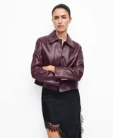 Chaqueta bordó de cuero sintético con cuello camisero, cierre frontal con botones oscuros y bolsillos de parche con solapa a la altura del pecho.