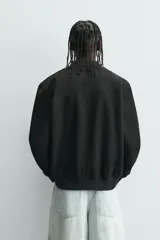 Cazadora bomber negra de corte regular fit, confeccionada en tejido efecto ante. Cuenta con cuello, puños y bajo en rib elástico, manga larga, bolsillos de vivo en la cadera y un bolsillo interior. Cierre frontal con cremallera.