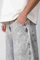 Pantalón de jean con corte baggy y fit oversize, de color gris con efecto lavado ácido. Presenta costuras reforzadas y diseño de pierna ancha.