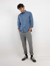 Camisa de hombre color azul, con cuello buttondown, cierre frontal con botones y logo bordado en el pecho. Presenta un acabado vintage logrado mediante el proceso de teñido en prenda.