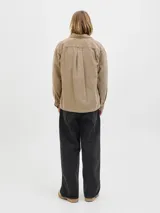 Sobrecamisa de manga larga confeccionada en pana, con cuello camisero, cierre frontal de botones, puños abotonados y un bolsillo en el pecho con etiqueta de marca. Presenta un corte relajado y textura acanalada.