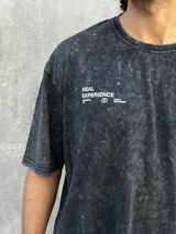 Remera gris con efecto lavado, corte oversize, manga corta y estampado pequeño en el frente.