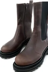 Bota de cuero color marrón chocolate, con elásticos laterales negros, cierre lateral y suela track color negro.