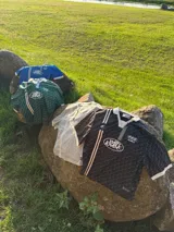 Polo de manga corta con cuello tipo polo y escote en V, corte boxy fit. Presenta un patrón texturizado en relieve y un logo ovalado con la inscripción "with love" en el pecho.