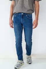 Jean de corte slim fit en color azul oscuro, con diseño clásico de cinco bolsillos, cierre frontal con botón y cremallera.