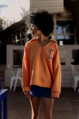 Buzo amarillo de algodón con cuello polo y bordes en azul. Presenta un bordado en el pecho con un diseño de sello postal.