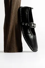 Ballerinas negras de cuero con correa sobre el empeine, hebilla metálica y tachas plateadas.