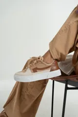 Zapatillas bajas color beige y marrón, con cordones y suela blanca.