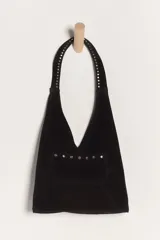 Bolso de hombro confeccionado en gamuza negra, con diseño de silueta slouchy y detalle de tachas metálicas en la correa y en el bolsillo frontal.