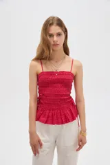Top de algodón con diseño estampado de cuadros vichy en tonos celeste y blanco, corte al cuerpo con escote recto y tirantes finos. Presenta cuerpo fruncido tipo smock con cordones ajustables en los laterales que forman un pequeño volado en el ruedo.