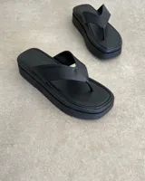 Ojota negra de plataforma con tira ancha de cuero vegano.