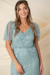 Vestido largo de tul bordado color verde agua, corte a la cintura y falda amplia. Las mangas son desmontables mediante broches, permitiendo usarlo sin mangas y combinarlo con un chal o túnica.