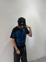 Remera negra de corte regular con estampado frontal de gran tamaño en serigrafía color azul, con diseño de caligrafía abstracta. Cuenta con cuello reforzado y grifa de la marca en la manga.