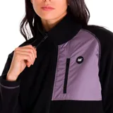 Campera polar negra para mujer, con cierre frontal completo, cuello alto y mangas largas. Presenta un bolsillo vertical con cierre en el pecho de color lila, con logo de la marca.