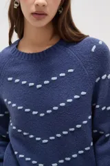 Sweater de punto color azul con diseño de fantasía en forma de líneas curvas punteadas en color celeste. Presenta cuello redondo a la base, mangas largas con puños acanalados y corte holgado.