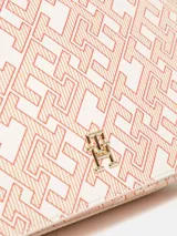 Cartera bandolera Tommy Hilfiger con estampado del monograma TH en tonos beige y rosa. Tiene correa ajustable, cierre con solapa, bolsillo interior con cremallera y logo metalizado TH en la parte delantera.