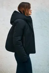 Anorak de corte corto y diseño minimalista, color negro. Cuenta con capucha integrada, cierre frontal con cremallera termosellada, bolsillos laterales con cierre y puños interiores elásticos. Posee acolchado interior y propiedades resistentes al agua y al viento.