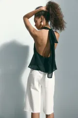 Bermuda de cinco bolsillos en denim de algodón rígido, corte baggy con cierre de botón y bajo deshilachado.