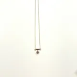 Collar dorado con cadena fina y dije circular negro.