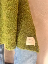 Chal de punto bouclé color marrón claro, hecho de 100% baby alpaca. Tejido suave, esponjoso y cálido, ofrece una textura envolvente y lujosa.