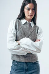 Chaleco de punto gris con diseño de rombos bordados en negro y cuello redondo. Presenta un corte clásico y tejido de textura suave.