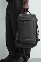 Mochila deportiva de diseño minimalista fabricada en tejido técnico resistente. Cuenta con compartimento principal con cierre de cremallera, bolsillo frontal con cierre, interior con bolsillo organizador, parte posterior acolchada con banda de sujeción para equipaje, asa superior y correas de hombro ajustables.