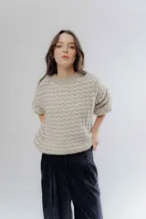 Buzo de punto grueso bicolor con textura marcada, cuello redondo y mangas largas con diseño holgado.