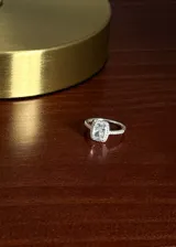 Anillo de plata 925 con diseño tipo Lady Di, presenta una zirconia rectangular central rodeada por un halo de zirconias pequeñas y pavé en los laterales del aro.