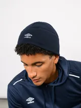 Gorro tipo beanie de polar color azul marino, con logo de la marca Umbro bordado en blanco en la parte frontal.