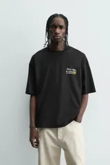 Camiseta negra de corte boxy fit, cuello redondo y manga corta, con estampado frontal en blanco y amarillo que dice "Social Media & Ciao Amore".