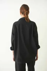Camisa negra de manga larga y corte semi holgado, con canesú en la espalda, abotonada en el frente y con cuello camisero.