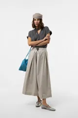 Pantalón wide leg color beige, con silueta amplia, pliegues delanteros y cintura definida.