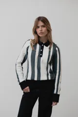 Buzo tipo polo de punto de algodón con diseño de rayas verticales en blanco y gris oscuro. Presenta cuello camisero negro, cierre frontal con botones y puños negros en las mangas y en el ruedo.