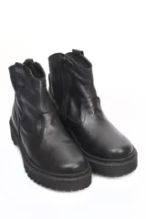 Botín de cuero negro con suela track dentada y cierre lateral. Presenta un diseño de caña baja con costuras reforzadas y acabado liso.