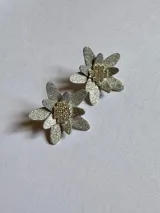 Par de aros dorados con forma de flor, con pétalos texturizados y centro de cuentas pequeñas.