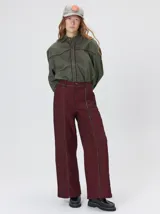 Pantalón sastrero de tiro medio, pierna ancha y corte recto, color bordó con finas rayas verticales y detalles de vivos a contratono en la pretina y el frente.