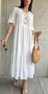 Vestido midi blanco con corte en capas, mangas cortas con volados y cuello redondo.