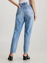 Pantalón de jean celeste con roturas en ambas piernas, de corte mom y tiro alto. Confeccionado con 79% algodón y 21% algodón reciclado.