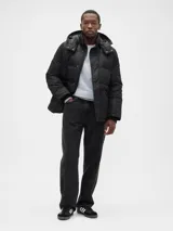 Campera puffer negra con capucha desmontable, cierre frontal con botones a presión y bolsillos laterales. Cuenta con puños internos acanalados para mayor protección contra el frío.