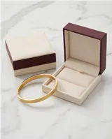 Pulsera tipo esclava rígida de acero con baño de oro, con diseño grabado de textura geométrica en forma de rombos.